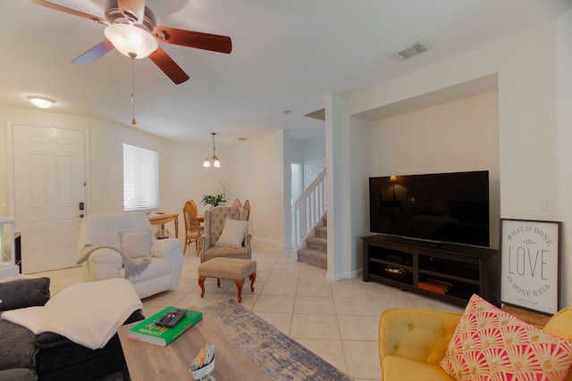 living area with a ceiling fan, stairs, light tile patterned flooring, and visible vents