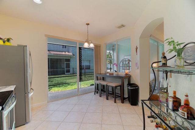 dining area featuring visible vents, arched walkways, a notable chandelier, and light tile patterned flooring