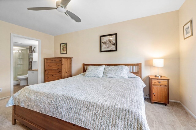 bedroom with baseboards, light carpet, ceiling fan, and ensuite bath