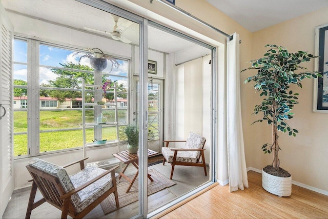 sunroom / solarium with baseboards, plenty of natural light, and wood finished floors