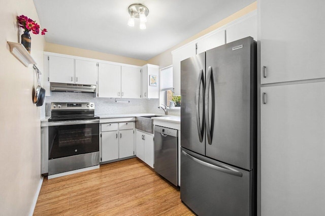 kitchen featuring light wood-style floors, light countertops, white cabinetry, under cabinet range hood, and appliances with stainless steel finishes