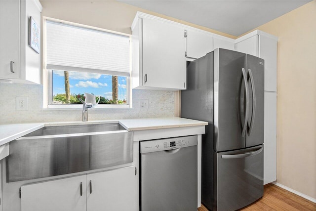 kitchen featuring a sink, decorative backsplash, stainless steel appliances, and white cabinetry