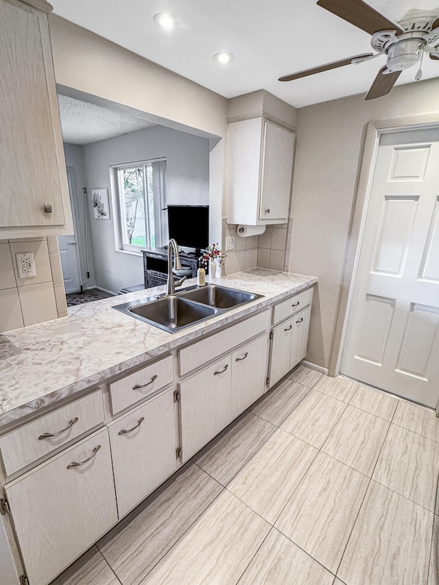kitchen with ceiling fan, backsplash, a sink, light countertops, and recessed lighting