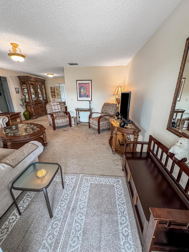 living room with baseboards, carpet, a textured ceiling, and visible vents