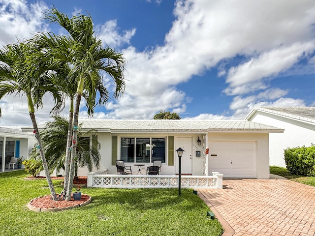 ranch-style house featuring an attached garage, a front lawn, stucco siding, a porch, and decorative driveway