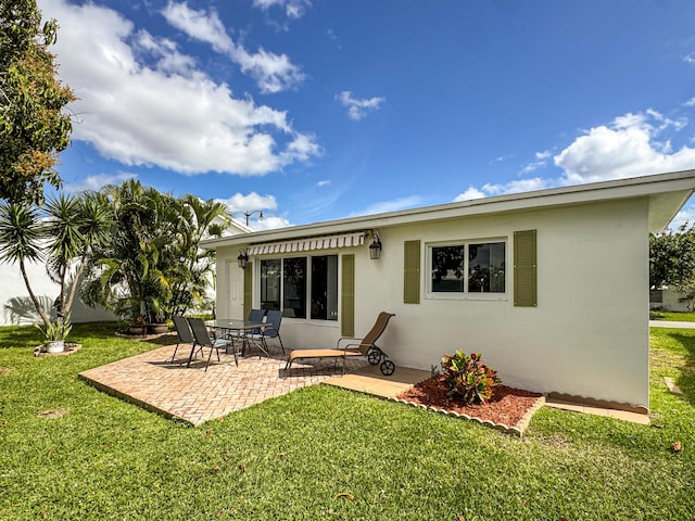 back of house featuring a patio, stucco siding, and a yard