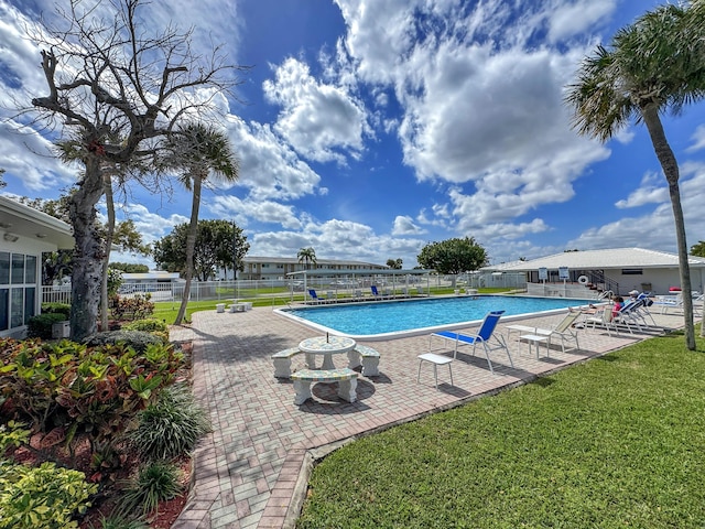 pool featuring a lawn, a patio area, and fence