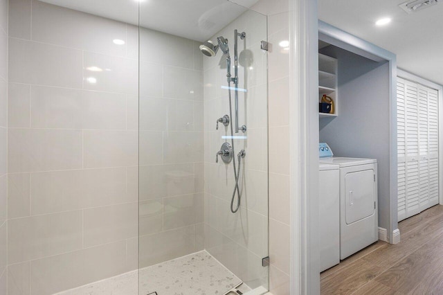 bathroom featuring visible vents, washing machine and clothes dryer, tiled shower, and wood finished floors