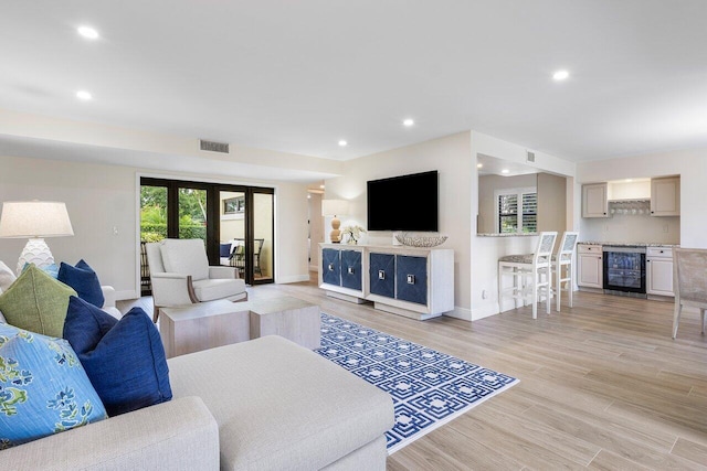 living room with visible vents, baseboards, beverage cooler, light wood-style floors, and recessed lighting