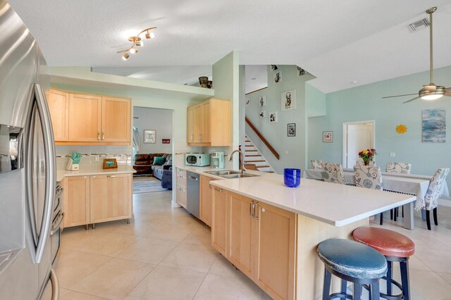 9681 Pine Trail Ct, Lake Worth, FL 33467 - kitchen featuring stainless steel appliances, light brown cabinetry, a peninsula, a breakfast bar area, and ceiling fan