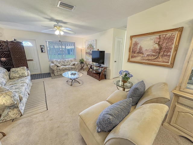 carpeted living room with visible vents, a ceiling fan, and a textured ceiling