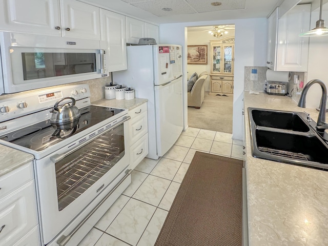 kitchen with light colored carpet, a sink, white appliances, light countertops, and white cabinetry