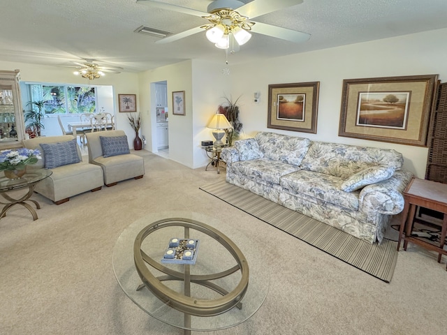 living area featuring carpet floors, a textured ceiling, ceiling fan, and visible vents