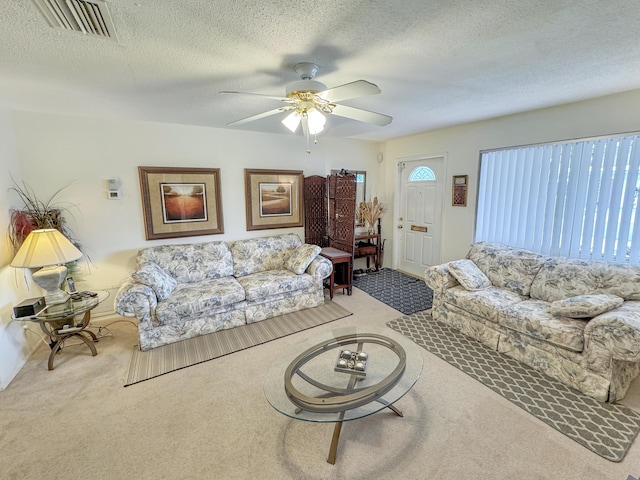carpeted living room with baseboards, ceiling fan, a textured ceiling, and visible vents