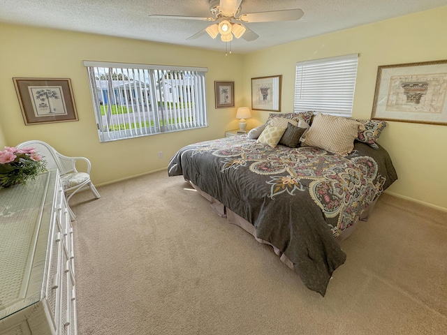 carpeted bedroom featuring baseboards, multiple windows, and ceiling fan