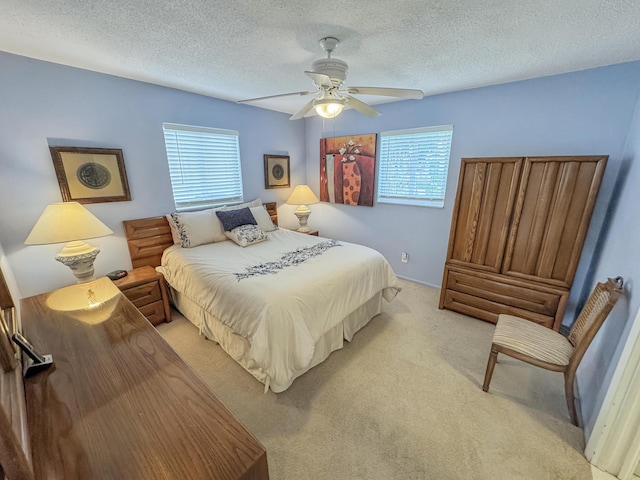 bedroom featuring light colored carpet, a ceiling fan, a textured ceiling, and multiple windows