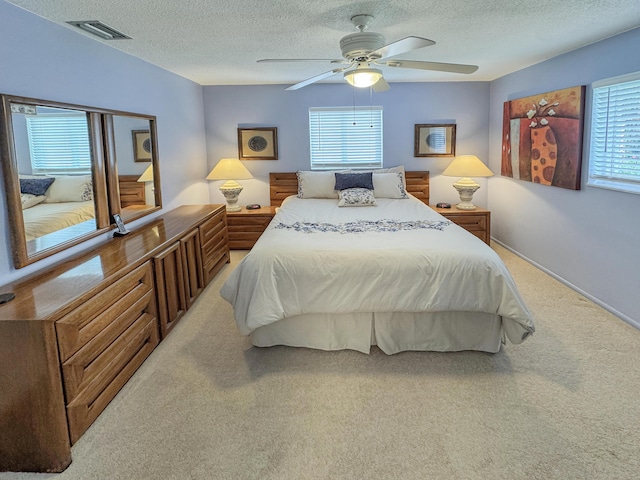 bedroom featuring carpet floors, a ceiling fan, a textured ceiling, and visible vents