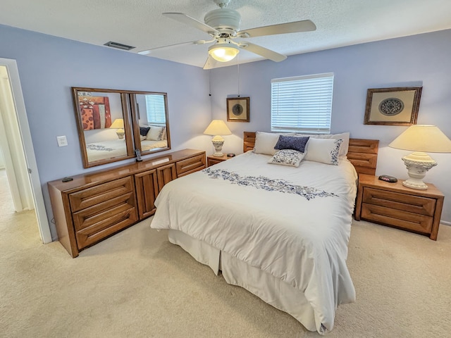 bedroom featuring a ceiling fan, visible vents, and light carpet