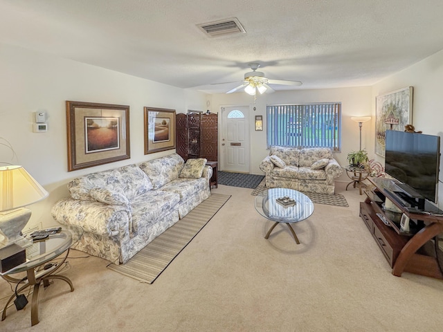 carpeted living area with visible vents and ceiling fan