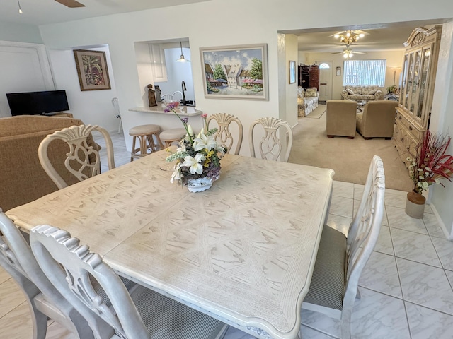 dining space with a ceiling fan and light carpet