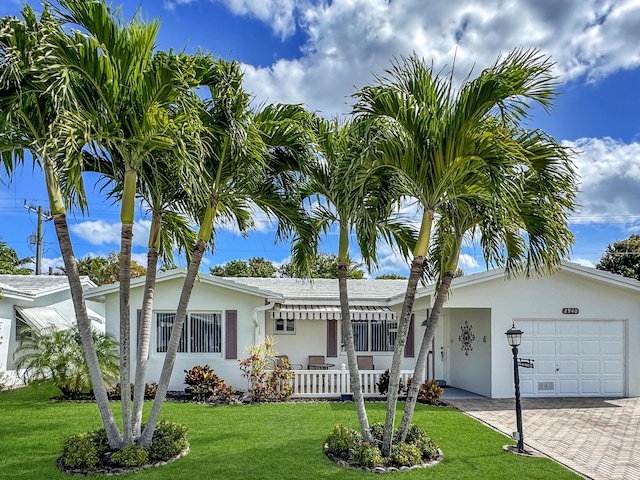 ranch-style home with an attached garage, decorative driveway, a front lawn, and stucco siding