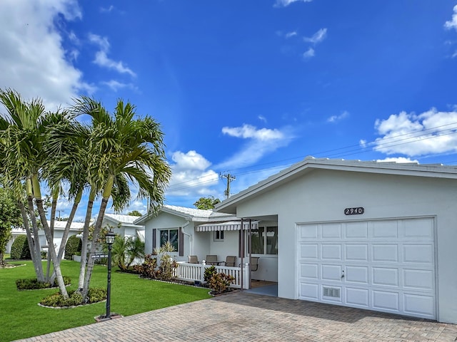 ranch-style home featuring a garage, decorative driveway, a front lawn, and stucco siding