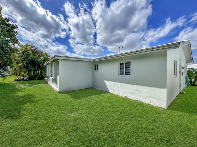 back of property with a lawn and stucco siding
