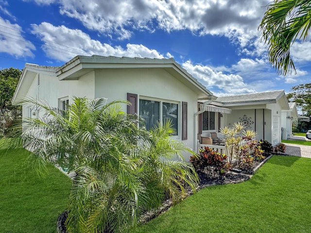 view of side of property featuring stucco siding and a yard
