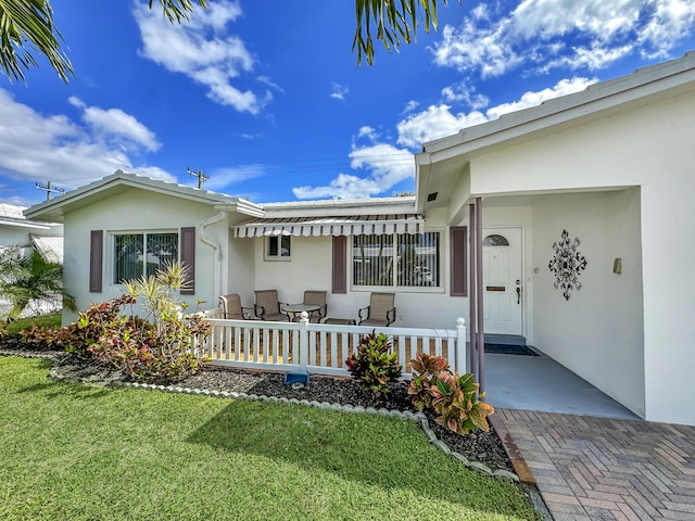 doorway to property featuring stucco siding and a yard