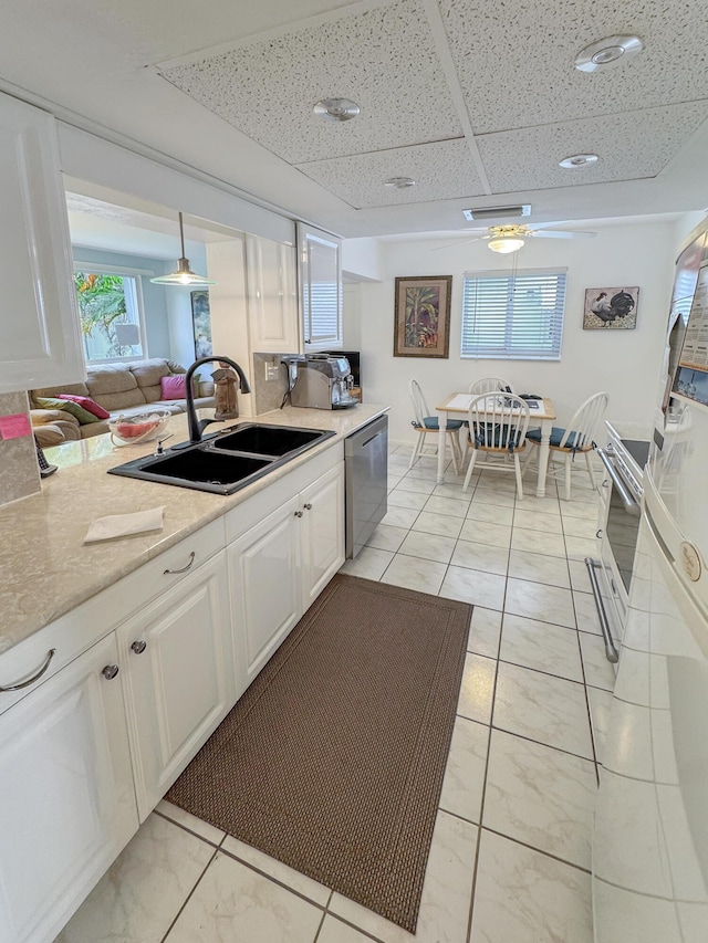 kitchen with a sink, dishwasher, light countertops, white cabinetry, and a ceiling fan