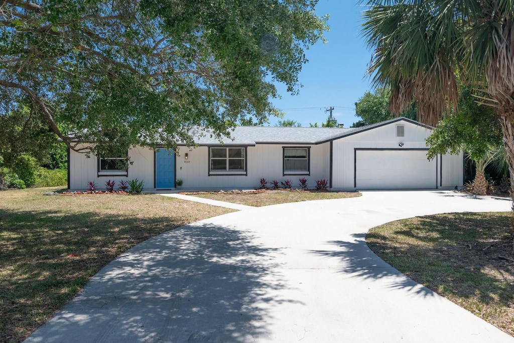 ranch-style home featuring concrete driveway, an attached garage, and a front yard