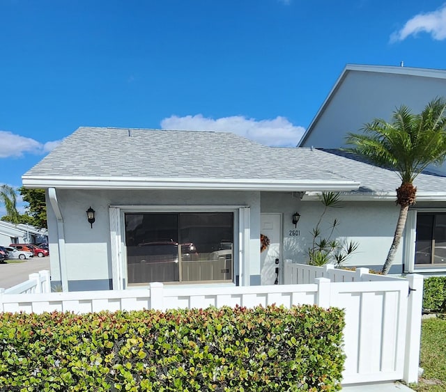 bungalow with fence, a shingled roof, and stucco siding