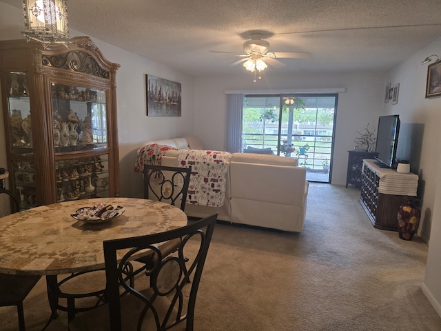 carpeted dining space featuring ceiling fan and a textured ceiling