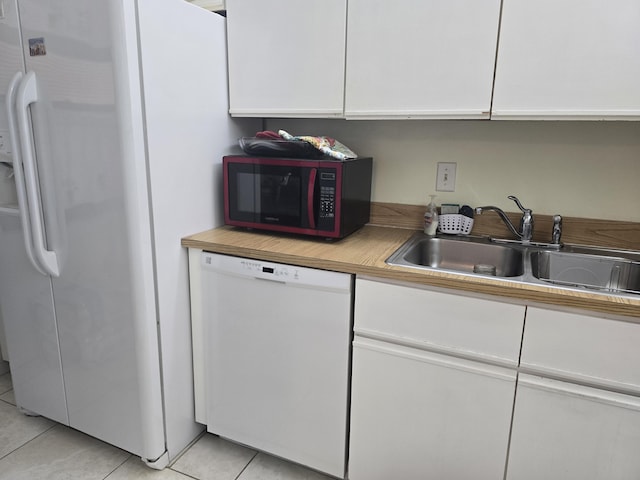 kitchen featuring light tile patterned flooring, white appliances, light countertops, white cabinetry, and a sink