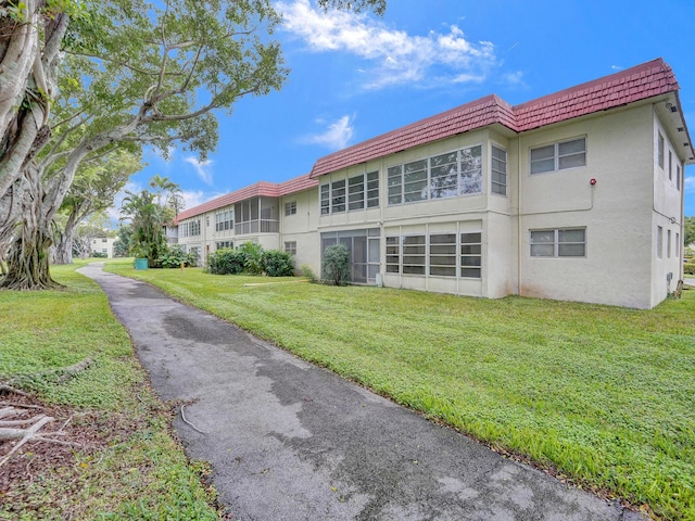 19 Abbey Ln Unit 203, Delray Beach, FL 33446 - rear view of property with a lawn, stucco siding, and mansard roof