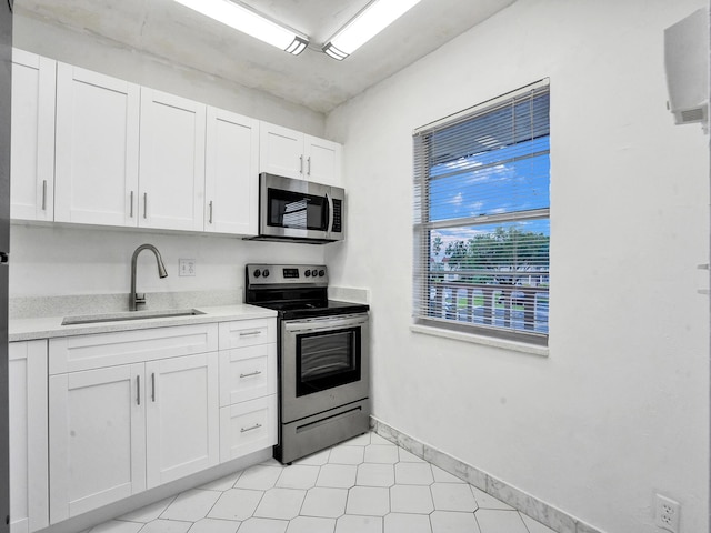 19 Abbey Ln Unit 203, Delray Beach, FL 33446 - kitchen with stainless steel appliances, baseboards, white cabinetry, and a sink