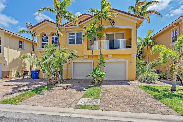 view of front of property with a garage, stucco siding, decorative driveway, a balcony, and a tiled roof