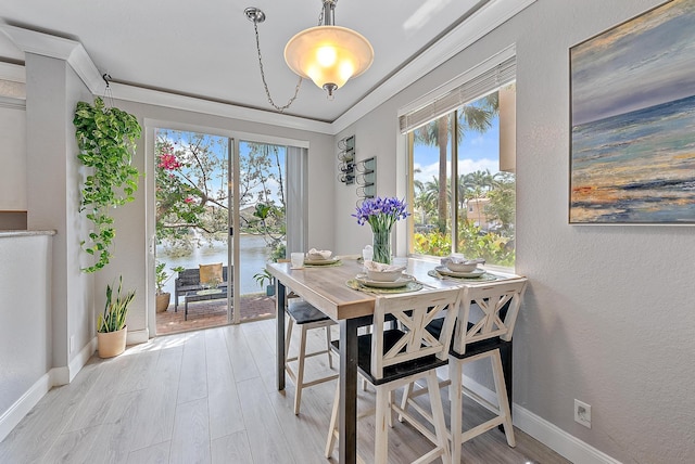 dining room with baseboards, light wood-style flooring, a water view, and a textured wall