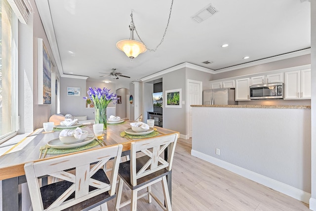 dining space featuring baseboards, ornamental molding, light wood-type flooring, and visible vents