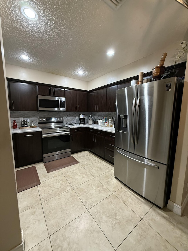 401 Shoreview Dr, Greenacres, FL 33463 - kitchen with stainless steel appliances, light countertops, decorative backsplash, a textured ceiling, and light tile patterned floors