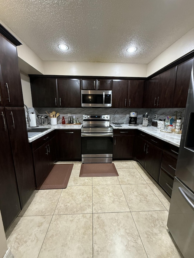 401 Shoreview Dr, Greenacres, FL 33463 - kitchen with appliances with stainless steel finishes, a textured ceiling, light countertops, tasteful backsplash, and dark brown cabinets
