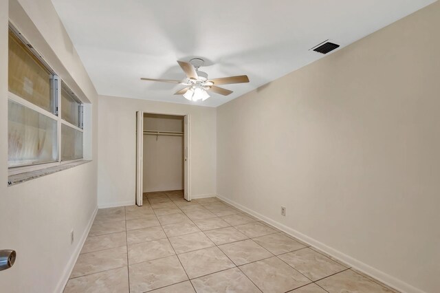 unfurnished bedroom featuring a closet, baseboards, ceiling fan, and light tile patterned floors