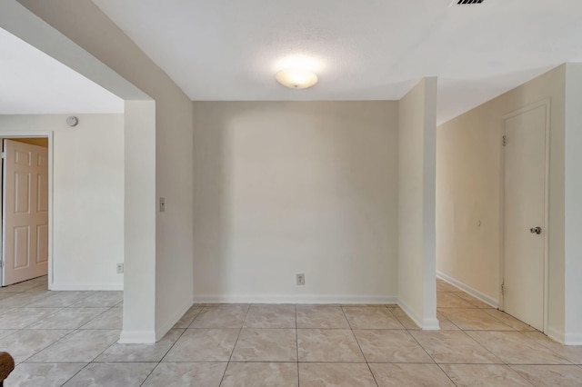 spare room featuring light tile patterned floors and baseboards