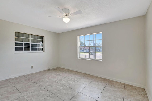 unfurnished room with a ceiling fan, light tile patterned floors, and baseboards