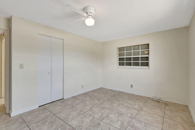 unfurnished bedroom featuring light tile patterned floors, a closet, a ceiling fan, and baseboards