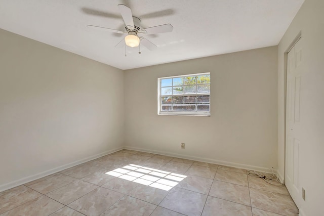 empty room with light tile patterned floors, ceiling fan, and baseboards
