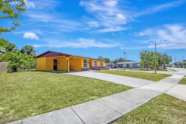 ranch-style house with driveway, a front lawn, an attached carport, and stucco siding