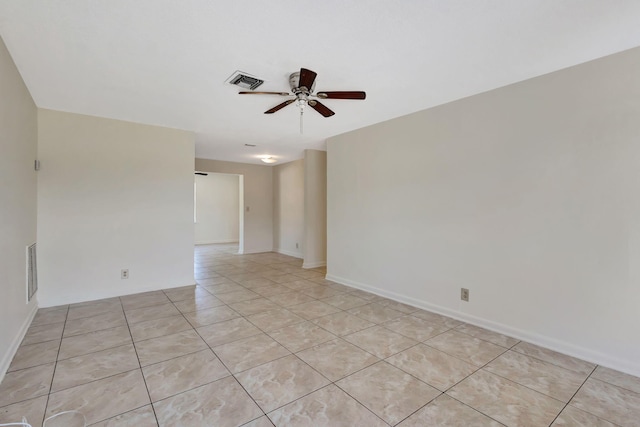 empty room with ceiling fan, light tile patterned floors, and baseboards