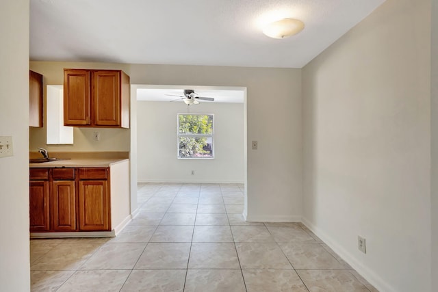 kitchen featuring ceiling fan, light countertops, light tile patterned floors, baseboards, and a sink