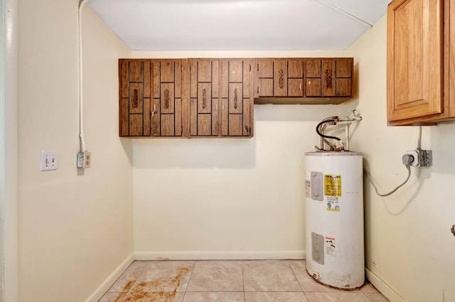 laundry room featuring cabinet space, electric water heater, hookup for an electric dryer, baseboards, and light tile patterned flooring